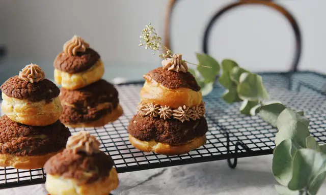 Délicieuses religieuses au chocolat, empilées sur une grille, ornées de crème et d'une touche de verdure.