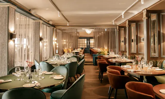 Elegant dining room at Hasselbacken restaurang, Stockholm. Tables set with glassware and cutlery, plush seating, and soft lighting create a sophisticated atmosphere.
