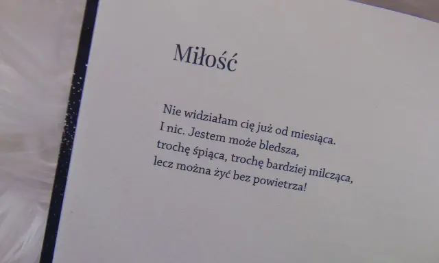 Otwarta książka z wierszem o miłości na jasnym tle.