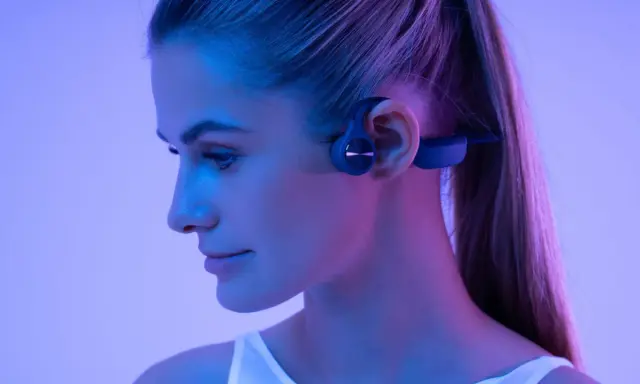 Une femme porte un casque à conduction osseuse. Ce type de casque peut présenter un danger si l'on n'est pas attentif à son environnement.