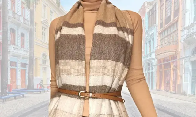 Modello che mostra come indossare una sciarpa grande a righe, abbinata a un dolcevita e una cintura sottile, con uno sfondo di edifici colorati.
