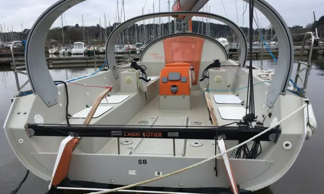 Le voilier "L'Abri Cotier" SB, un modèle kaidoz 31, est amarré dans un port. Son design moderne avec une arche distinctive est visible.