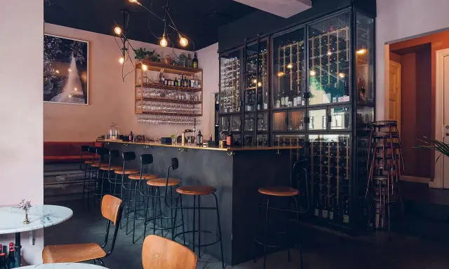 Mysig vinbar i Stockholm med en stor vinkyl, bardisk och sittplatser.