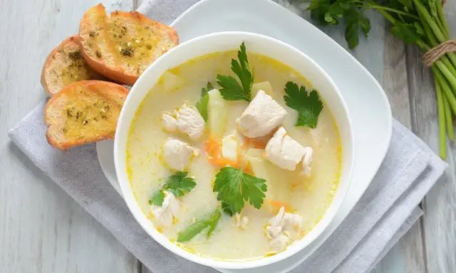 Aromatyczna zupa z kurczakiem z kawałkami mięsa, ziemniaków i marchewki, podana z grzankami czosnkowymi.