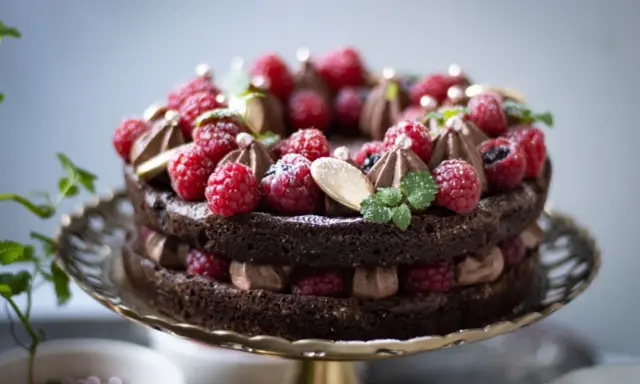 En lyxig kladdkaka med fluffig chokladmousse, toppad med färska hallon, mynta och guldkulor. Perfekt för en speciell fikastund.
