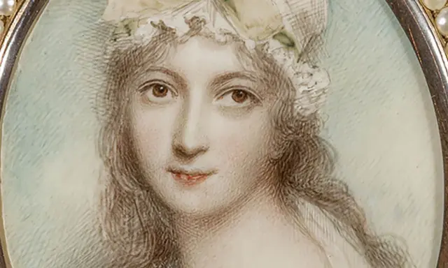 A delicate miniature portrait of a woman in a bonnet, framed by pearls. This tiny artwork captures a moment in time, showcasing the artistry of miniature portraits.