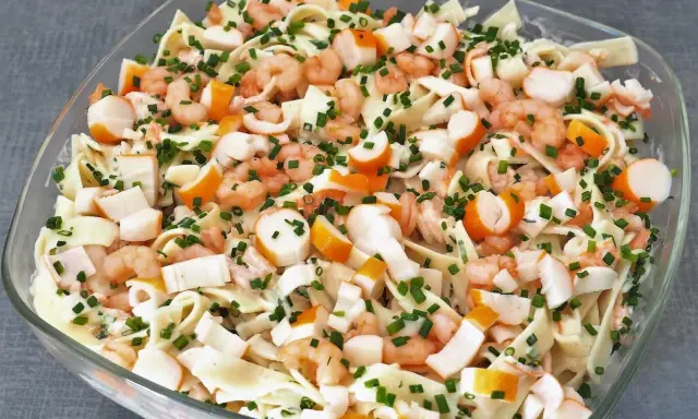 Salade Marco Polo : pâtes, crevettes, bâtonnets de surimi et ciboulette dans un plat en verre.