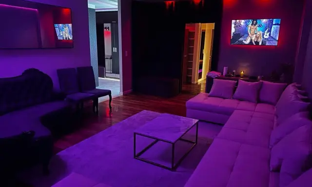 Nowoczesny salon z fioletowym oświetleniem. Na ekranie telewizora widać scenę, która może sugerować, czym jest swingowanie.