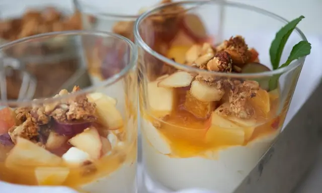 Leckeres Joghurt Dessert mit Früchten und Granola in Gläsern, garniert mit Minze.