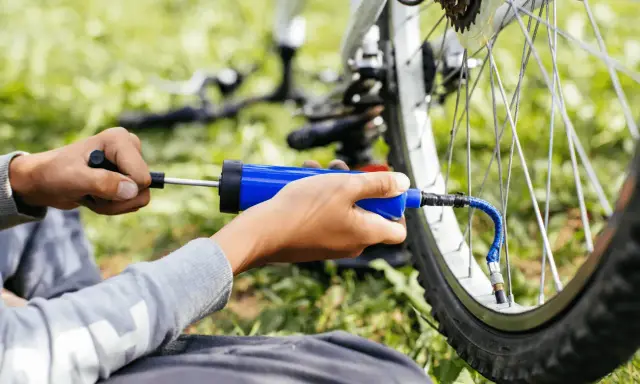 Ręce pompują rowerową oponę przez wentyl schrader.