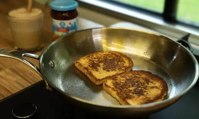 Dos tostadas francesas dorándose en una sartén de acero inoxidable, mostrando las ventajas e inconvenientes de este material para cocinar.