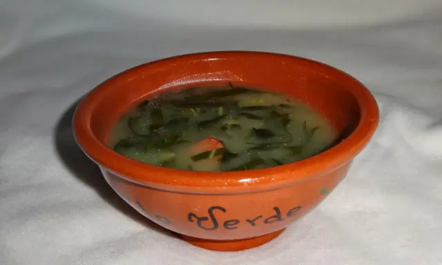 Un bol en terre cuite orné du mot "Verde" contient un délicieux caldo verde, une soupe portugaise réconfortante aux légumes verts.