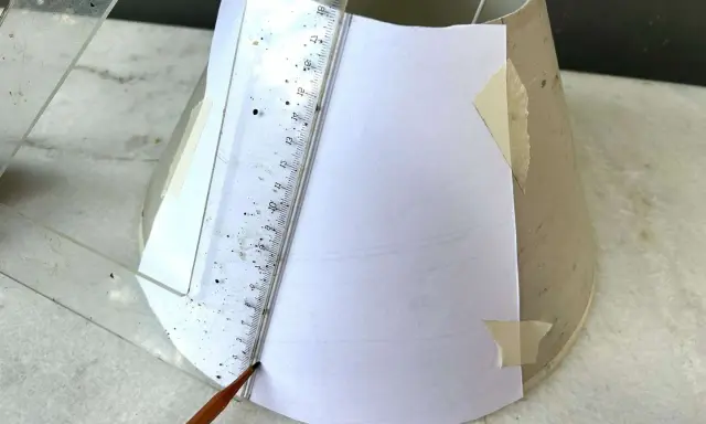 Un crayon et une règle marquent un gabarit en papier sur un abat-jour DIY.