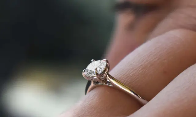 Un anello di fidanzamento con diamante solitario, un classico tra i tipi di anelli di fidanzamento, brilla su un dito.