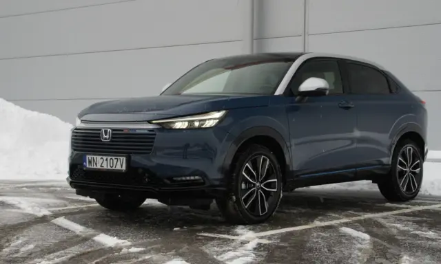Ciemnoniebieski Honda HR-V na tle śniegu i szarej ściany.
