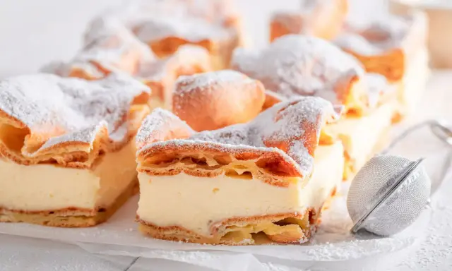 Kremówka papieska, jeden z 10 najlepszych ciast, posypana cukrem pudrem.