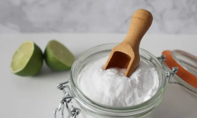 Bicarbonato e lime, ingredienti naturali per combattere la forfora. Un cucchiaino di bicarbonato in un barattolo di vetro.