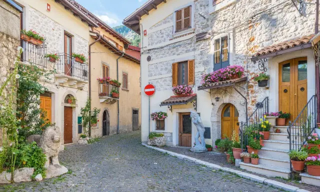 Antica via acciottolata tra **borghi Abruzzo sul mare**, con case in pietra e fiori colorati sui balconi.