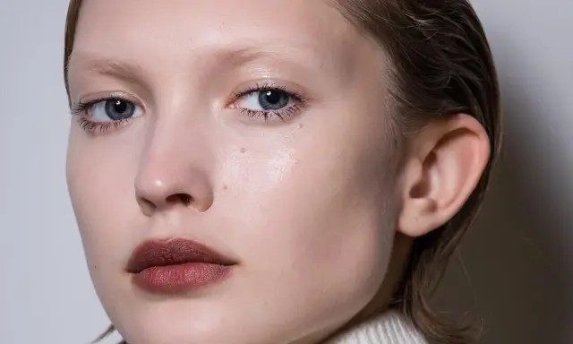 Primer plano de un rostro cuadrado con ojos azules y labios oscuros.