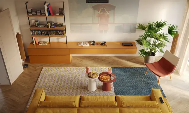 Un divano giallo accogliente, tavolini con pizza e popcorn, e una proiezione sul muro: perfette idee salotti piccoli per serate cinema.