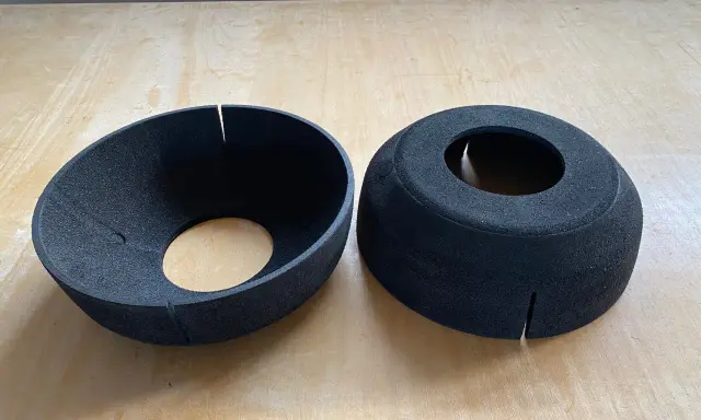 Zwei schwarze EPP-Platten, geformt wie Trichter und Zylinder, liegen auf einer Holzoberfläche.
