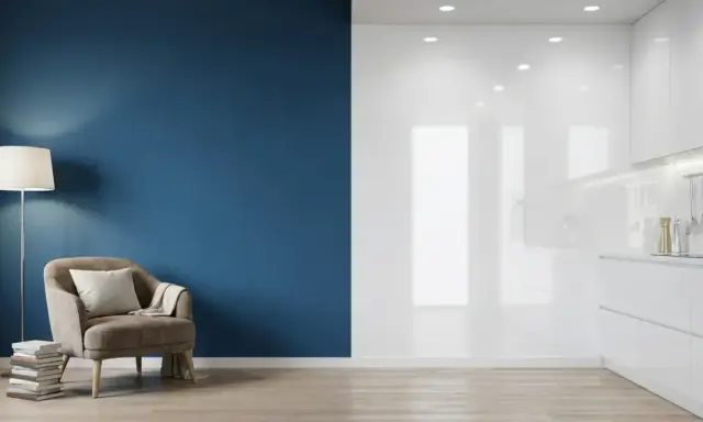 Un fauteuil confortable près d'un mur bleu profond, contrastant avec une cuisine blanche aux finitions peinture mat ou satin.