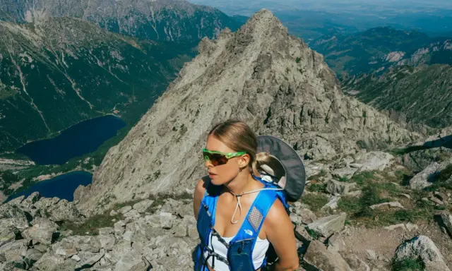 Kobieta w okularach i niebieskim plecaku na tle górskich krajobrazów. Beskid Śląski oferuje takie widoki i atrakcje.