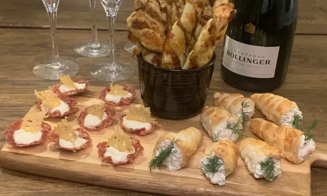 En flaska Bollinger och en bricka med läckra tilltugg till bubbel: små salta korgar, smördegsrullar och ostpinnar.