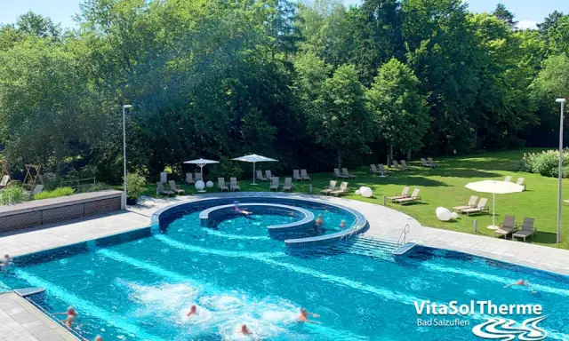 Außenpool der VitaSol Therme Bad Salzuflen mit Liegen und Bäumen.