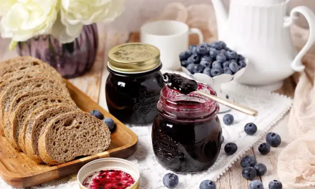 Un petit-déjeuner gourmand avec du pain de campagne, des myrtilles fraîches et une délicieuse confiture de myrtilles.