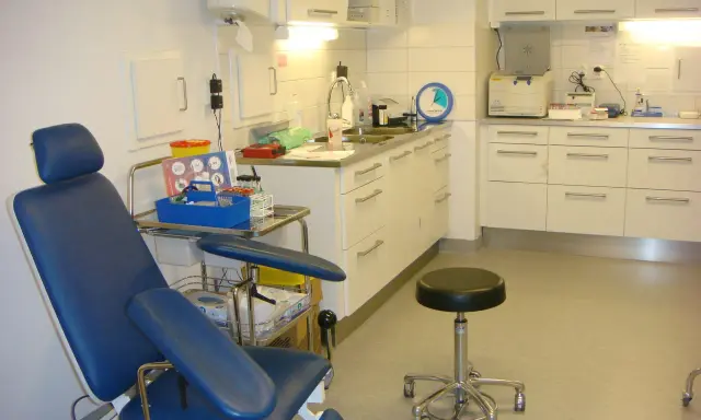 Blå undersökningsstol och medicinsk utrustning i ett kliniskt rum. Förberedelser för att testa för tyfoidfeber.