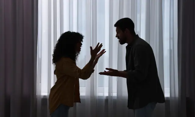Siluetas de una pareja discutiendo apasionadamente. Ella gesticula con las manos, él la mira fijamente. ¿Será que porque atraigo a personas con problemas?