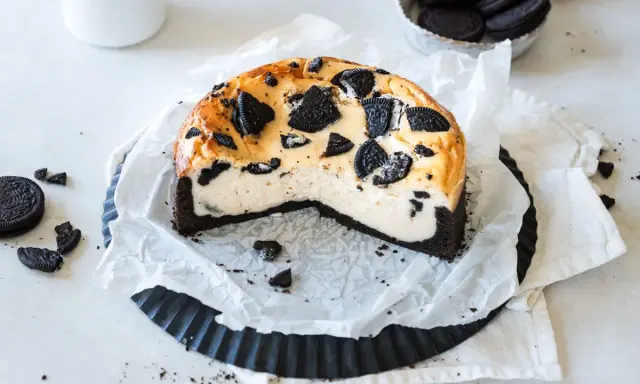 Ein cremiger Oreo Kuchen mit einem dunklen Keksboden, dekoriert mit ganzen und zerbrochenen Oreos.