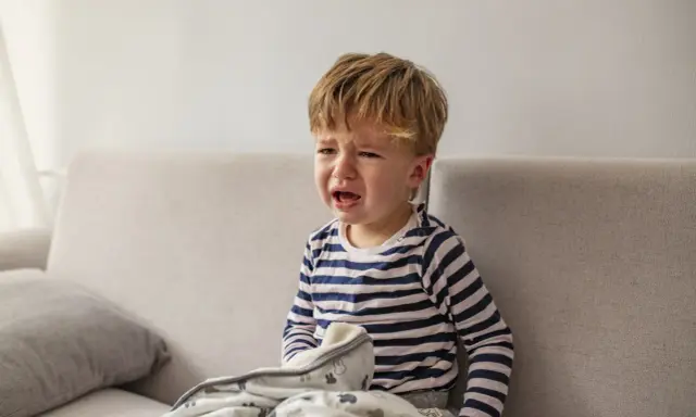 Mały chłopiec płacze na kanapie, przykryty kocykiem. Czyżby to był regres snu, kiedy?