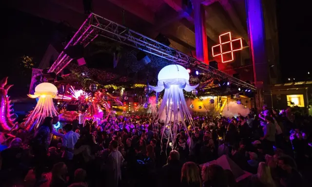 En livlig nattklubb i Stockholm med uppblåsbara maneter, discokulor och en stor publik som dansar under neonljus.