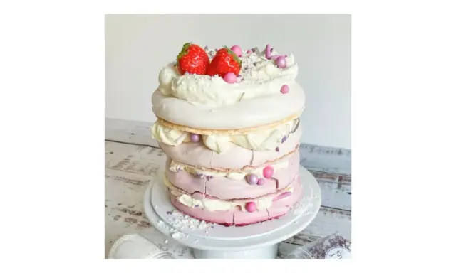Eine mehrstöckige Baiser Torte mit Sahne, Erdbeeren und rosa Zuckerperlen.