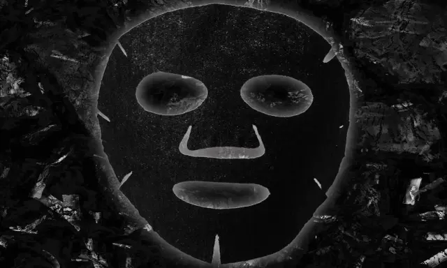 Maschera al carbone, con i suoi benefici, appare come un volto misterioso incorniciato da texture scure e profonde.