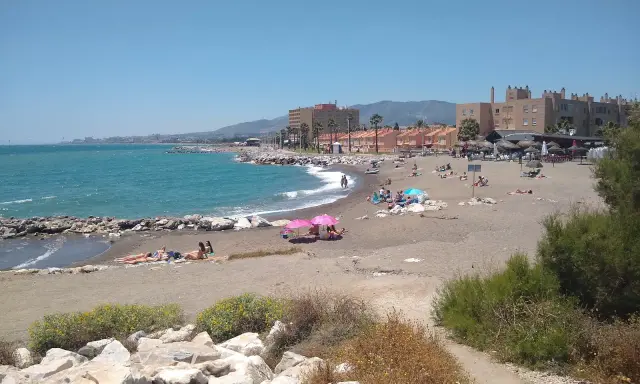 Sonniger Tag am playa de guadalmar mit Menschen, die sich am Strand sonnen und im türkisfarbenen Meer schwimmen.