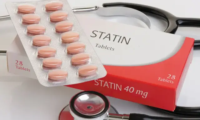 Opakowanie tabletek statynowych i blister z tabletkami. Stetoskop w tle. Statyny na co? Na obniżenie cholesterolu.