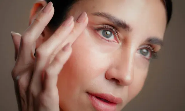 Une femme applique un soin sur son visage. Attention, l'acide hyaluronique peut parfois assécher la peau si mal utilisé.