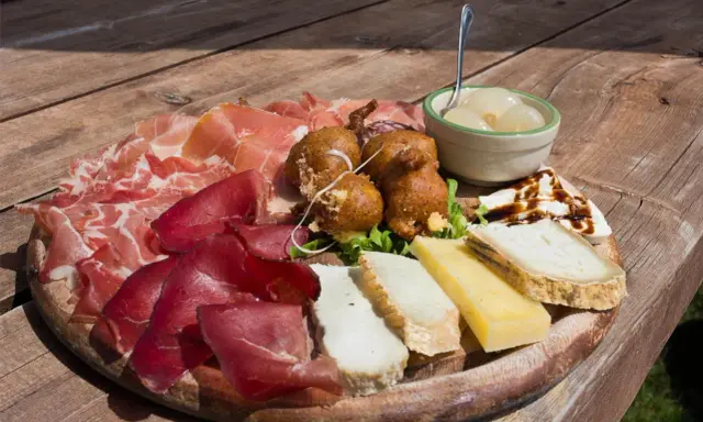 Tagliere con salumi, formaggi, frittelle e cipolline, un assaggio dei piatti tipici Valtellina.