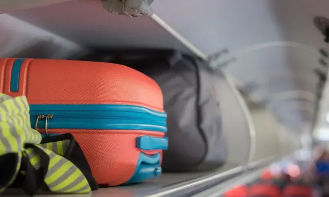 Pomarańczowa walizka i szara torba jako flydubai bagaż podręczny w schowku nad siedzeniami.