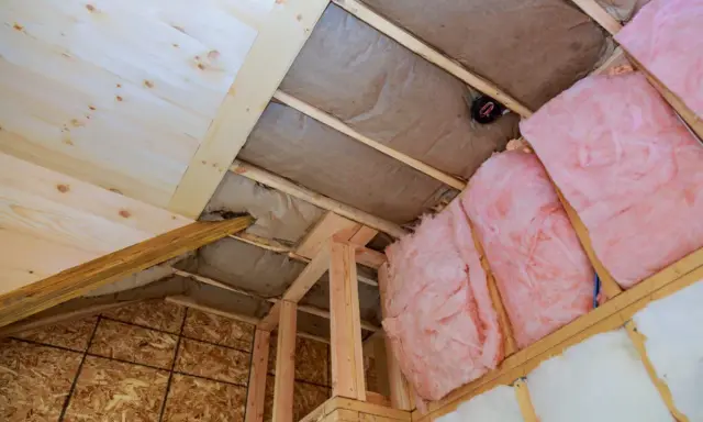 Proceso de como aislar un techo por el interior con lana de vidrio rosa y material de madera.