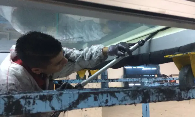 Un trabajador aplica **silicona estructural** en una junta de ventana.