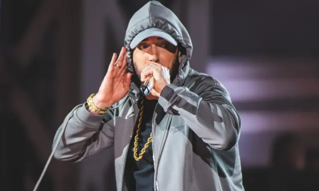 Eminem w kapturze i czapce, z mikrofonem w dłoni, jakby szykował kolejny eminem diss. Złoty łańcuch błyszczy.