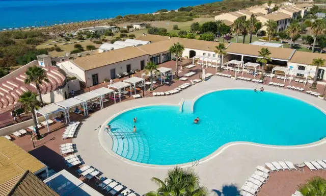 Vacanze al Sikania Eco Resort: piscina azzurra, lettini, palme e il mare all'orizzonte.