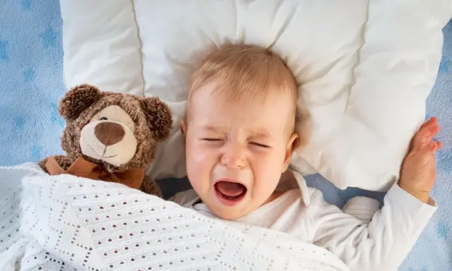 Bebé llorando en la cama con su osito de peluche. Mi hijo de 2 años se despierta mucho por la noche.