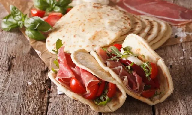 Piadina romagnola, un piatto tipico di Rimini, farcita con prosciutto crudo, pomodorini e rucola.