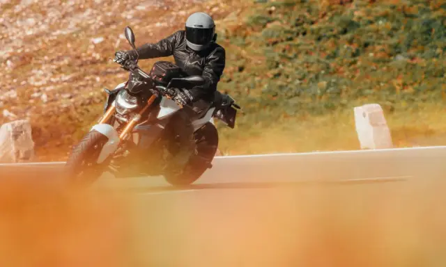 Motociclista con casco y chaqueta de cuero en una moto deportiva, disfrutando de la carretera. Ideal para quienes buscan el permiso conducir A1.