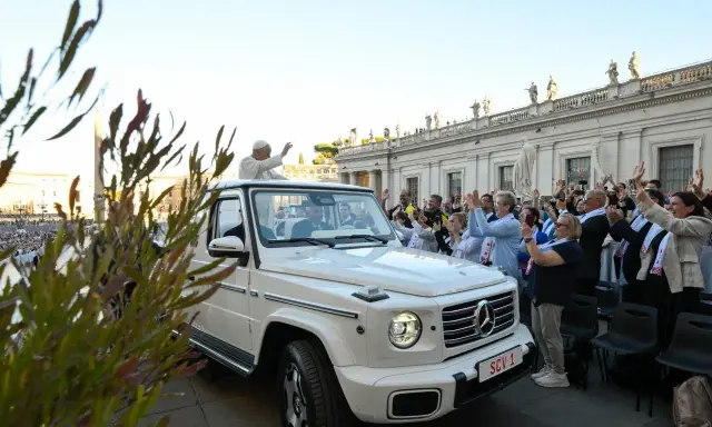 Papież Franciszek, mimo swojego vatican wiek, pozdrawia wiernych z białego mercedesa. Tłum wiwatuje, a niektórzy robią zdjęcia.